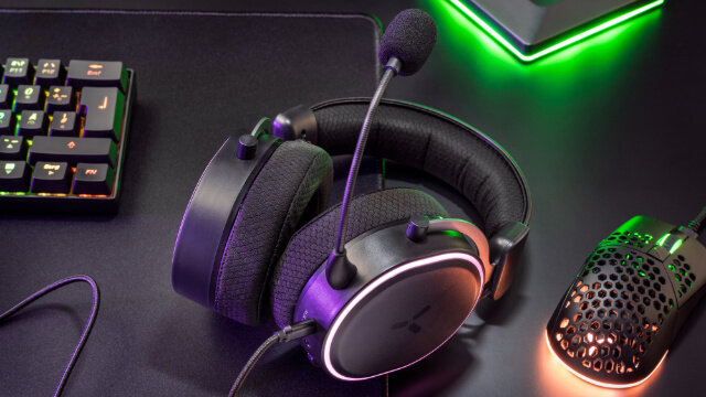 Casque et souris de jeu sur une surface noire avec des lumières vertes et violettes.