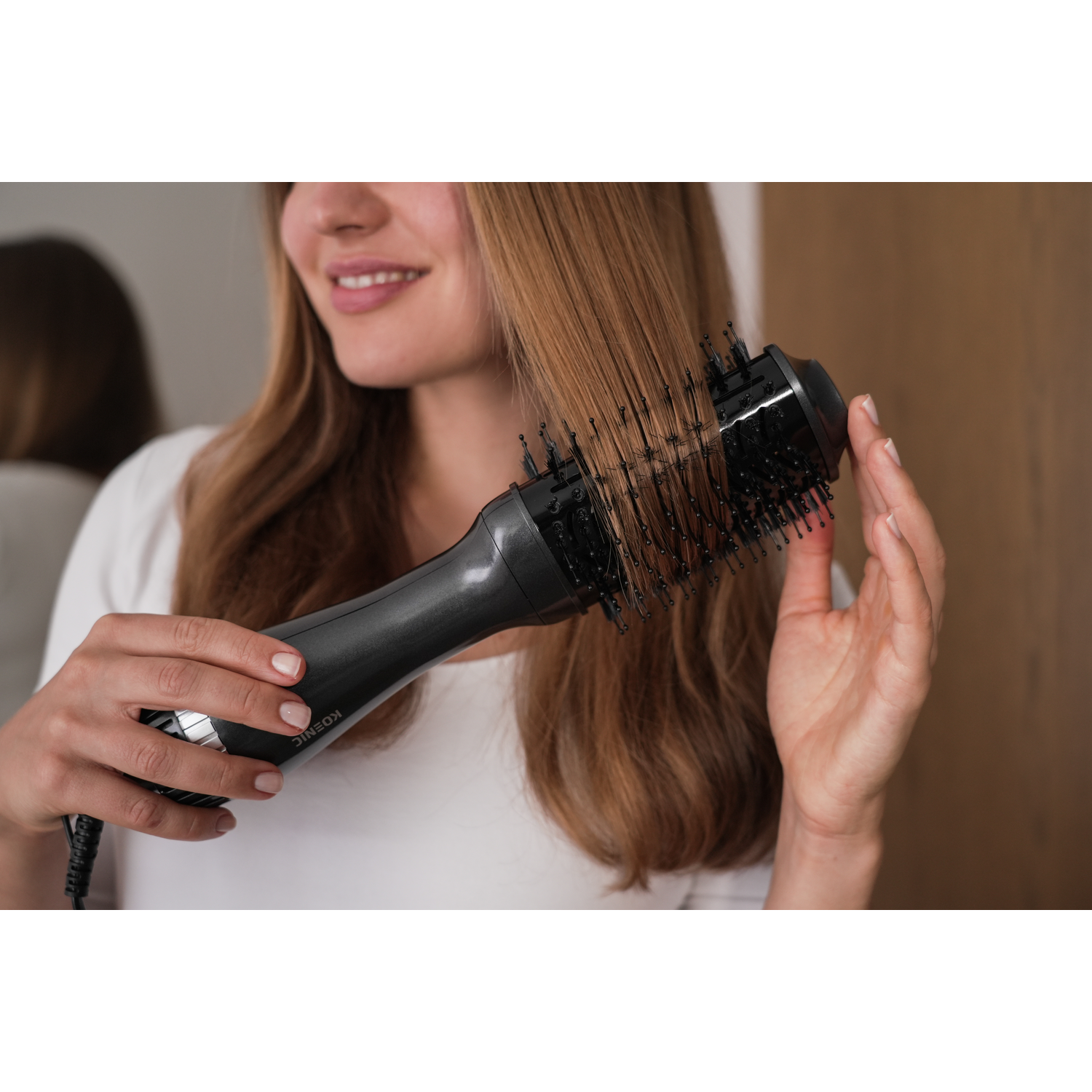 Woman using a hair styling brush. Dark gray brush, with black bristles, on the woman's hair.