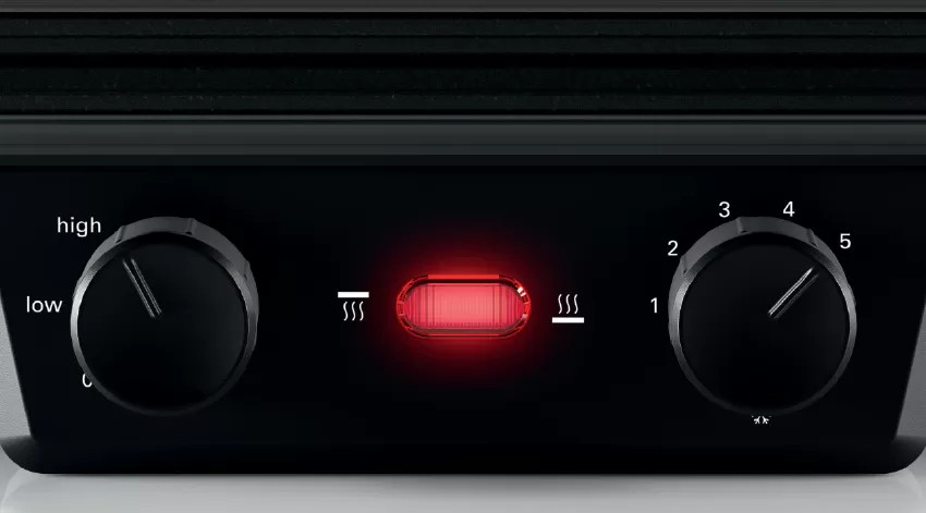 Czarne elementy sterujące urządzeniem z pokrętłami i czerwonym światłem.