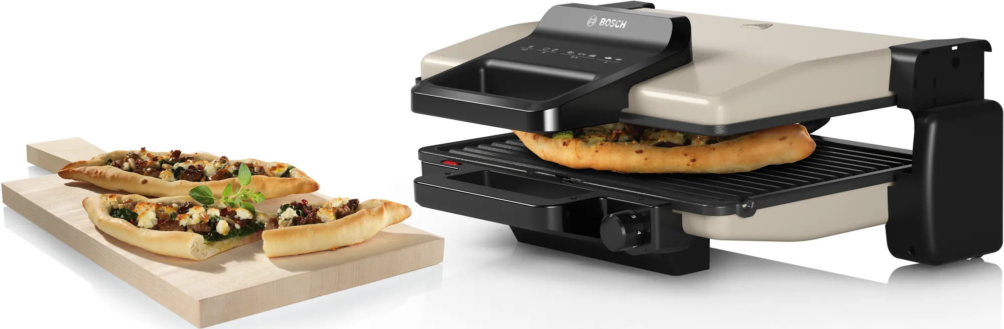 Grill Bosch z pizzą na nim i dwie pizze na drewnianej desce na białym tle.