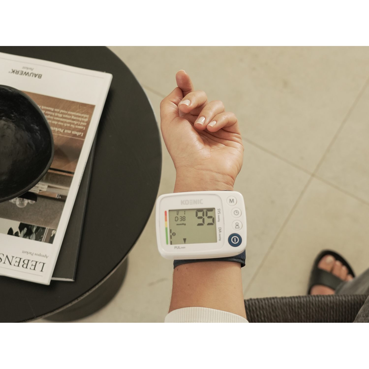 A person's wrist with a blood pressure monitor displaying numbers.
