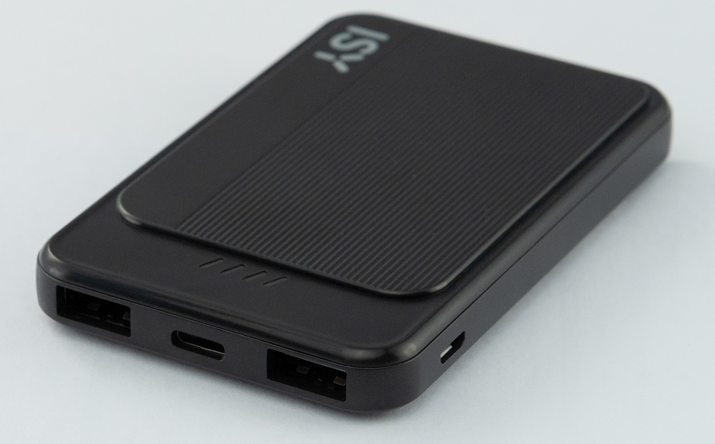 Czarny power bank, widok pod kątem, z portami USB, portem ładowania i teksturowaną górą.