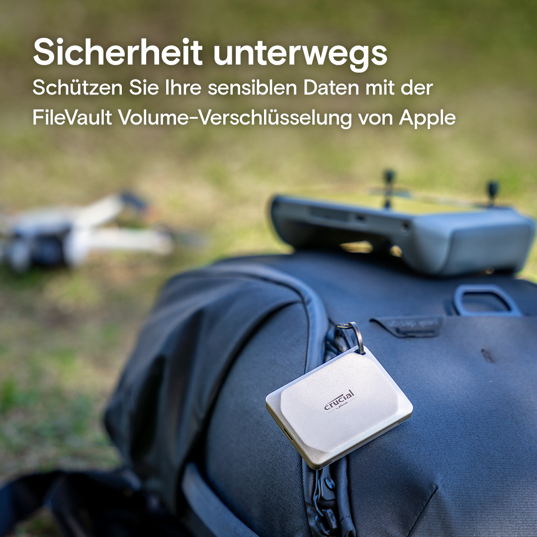 Eine Person hält ein weißes Gerät auf einem Rucksack, Drohne im Hintergrund.