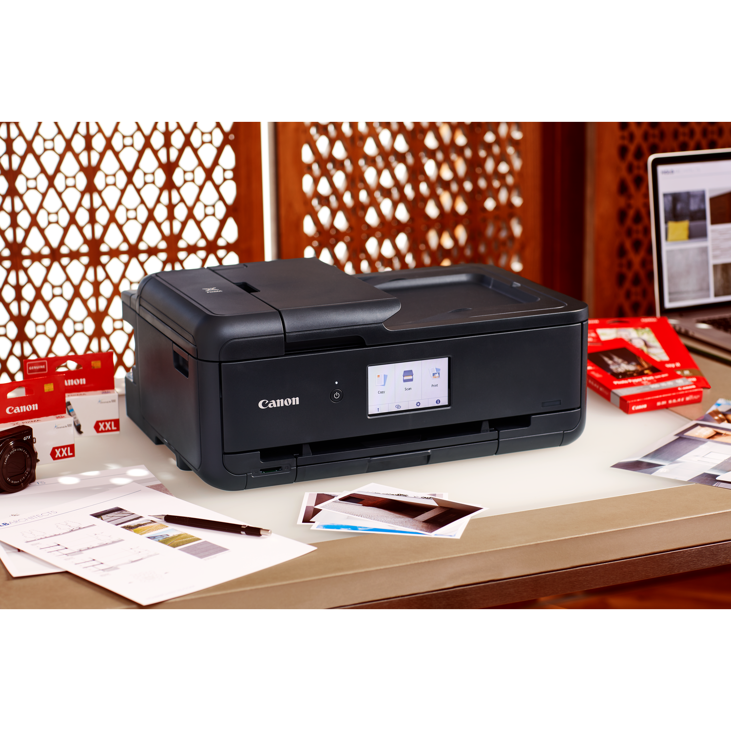 Black Canon printer on a desk with documents and accessories.