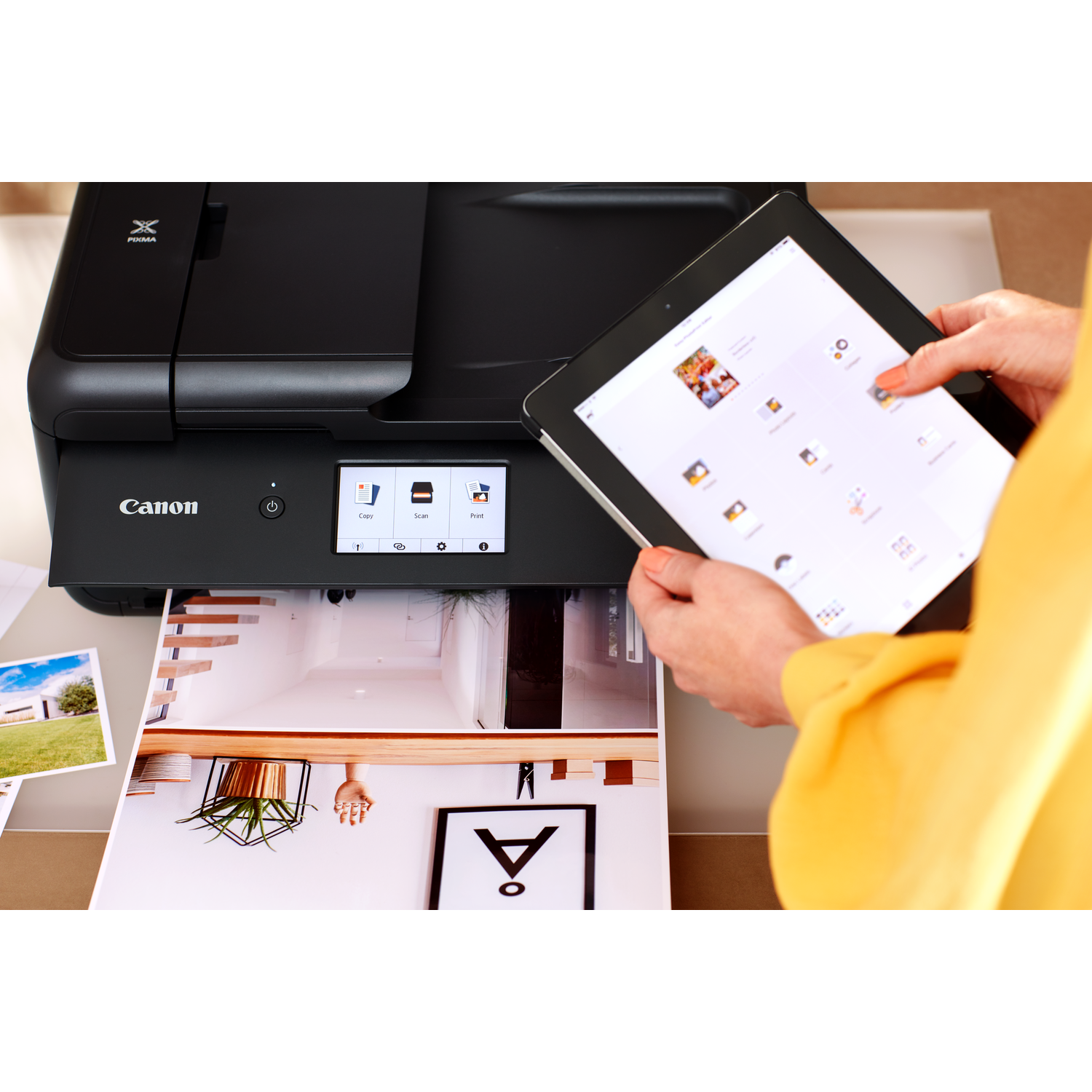 A printer with a tablet displaying a photo, and a printed image of a house.
