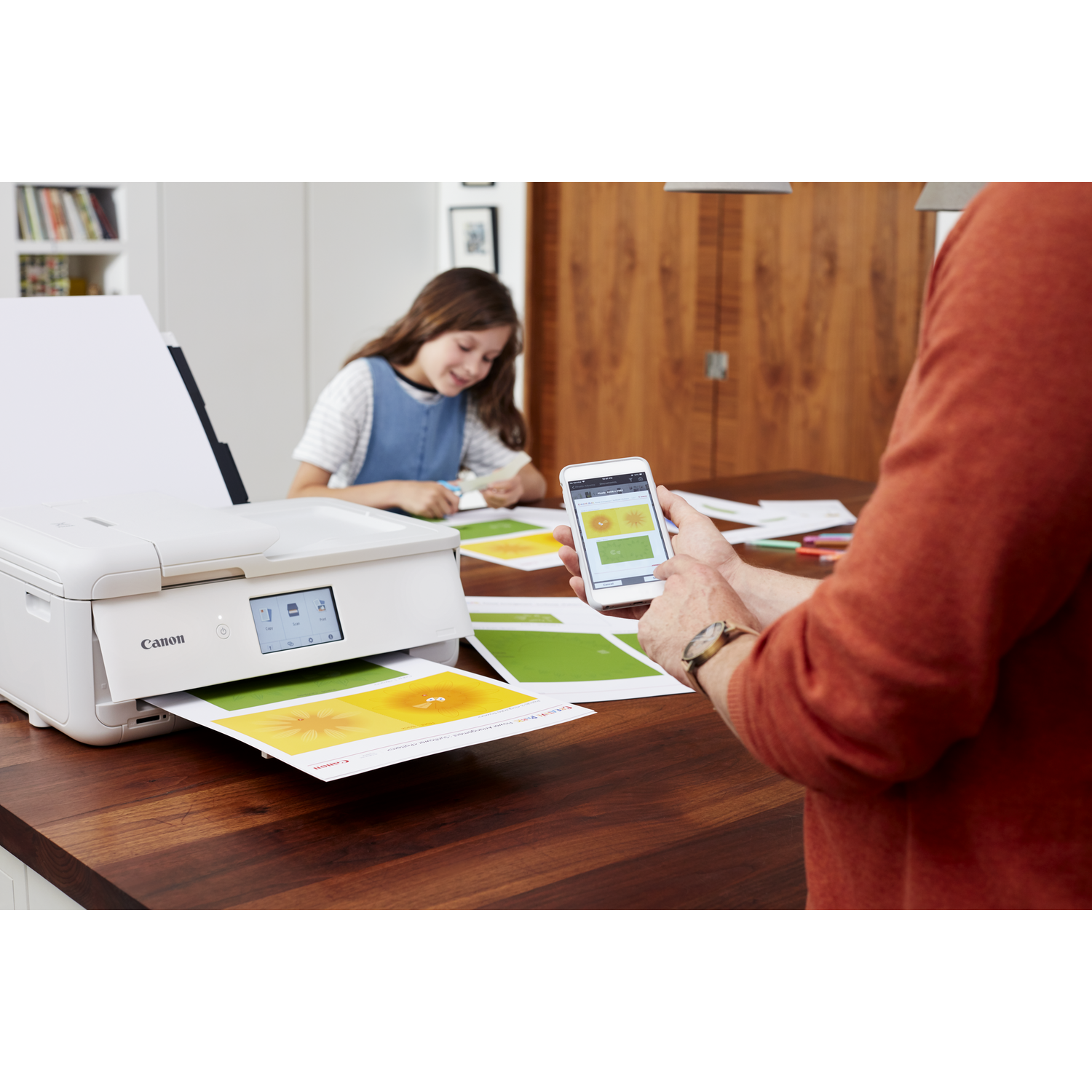 A person using a phone and a printer printing colorful papers. Another person is in the background.
