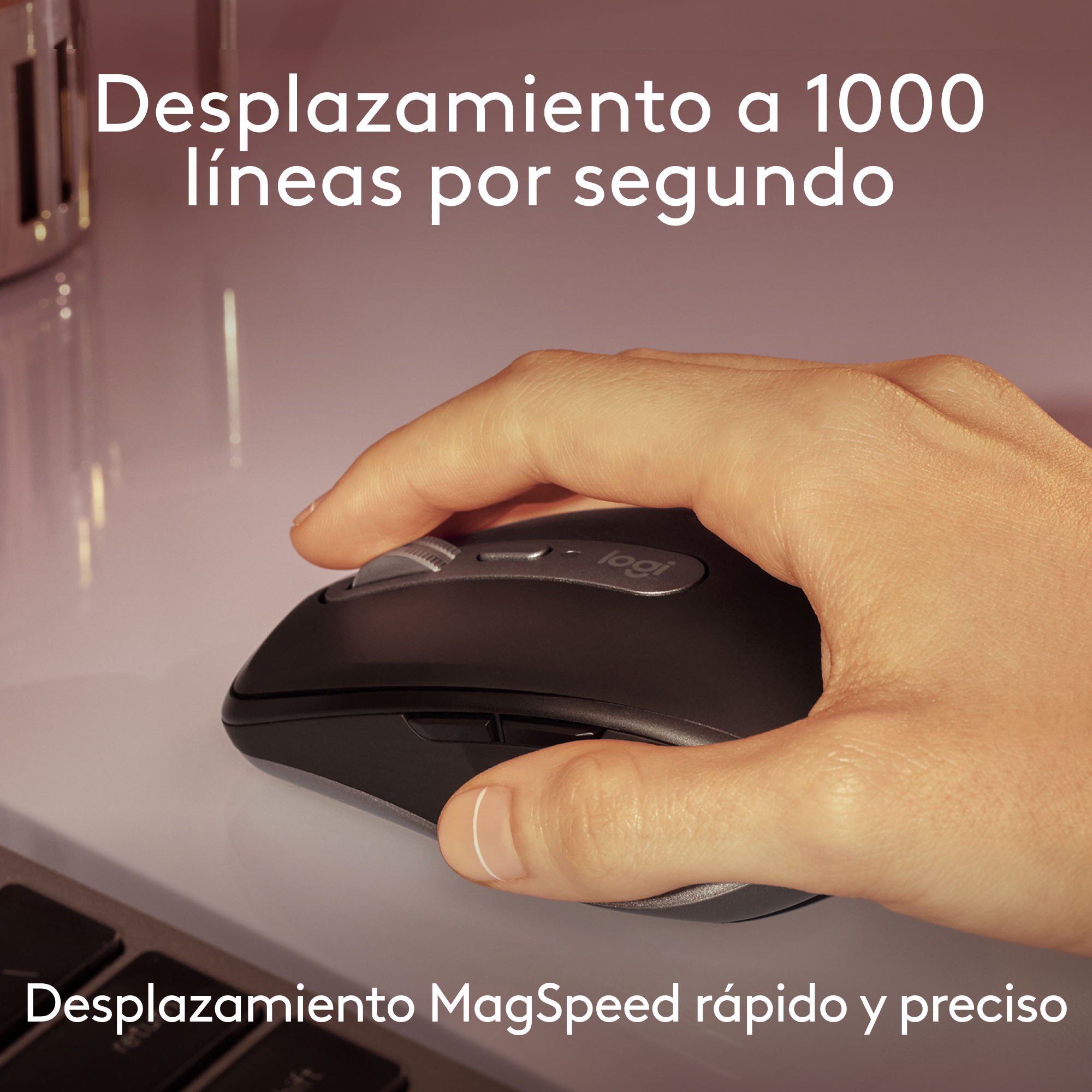 Mano usando un ratón Logitech negro sobre una superficie blanca, texto en español.