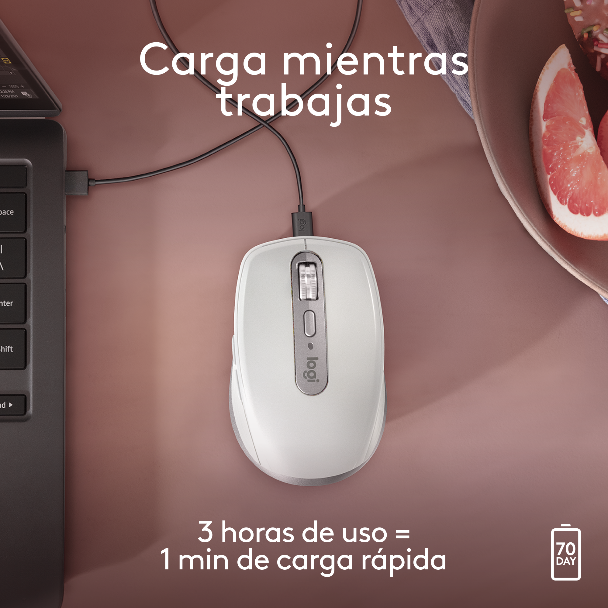 Un ratón de ordenador blanco con un cable de carga. Un portátil y un pomelo también están presentes en la mesa.