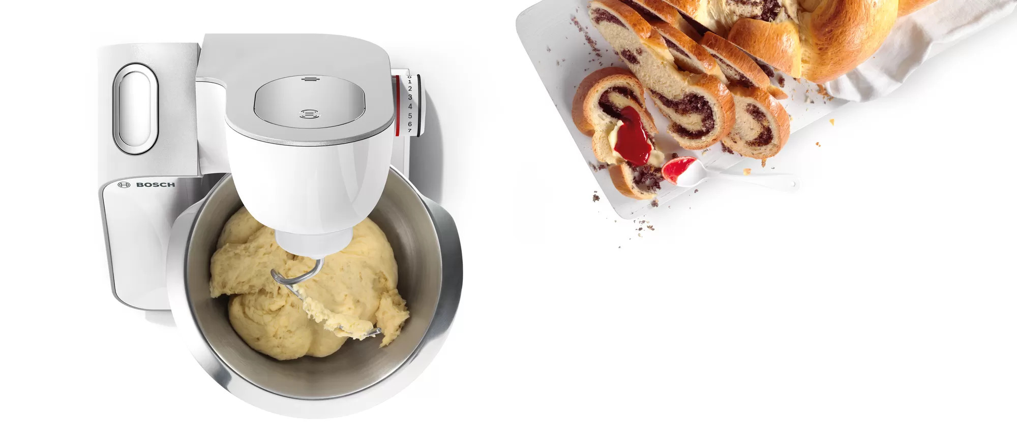 Biała maszyna kuchenna z hakiem do ciasta i miską z ciastem, obok pokrojonego chleba.