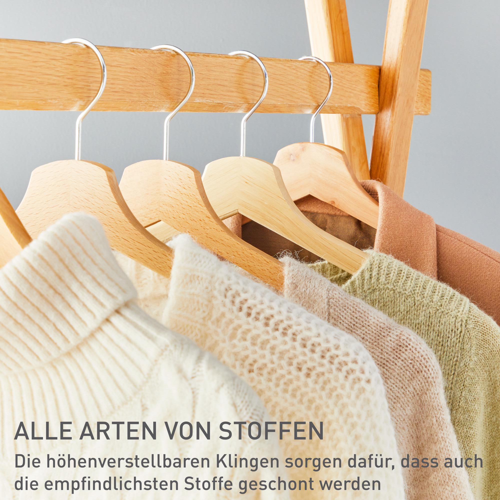 Nahaufnahme von Holzkleiderbügeln mit Kleidung, die auf einem Holzregal hängt.