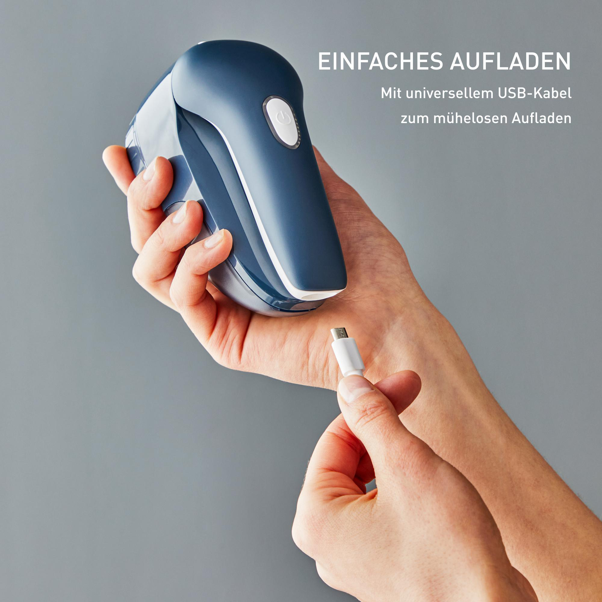 Hände, die einen blau-weißen Stoffrasierer halten; ein USB-Kabel wird eingesetzt.