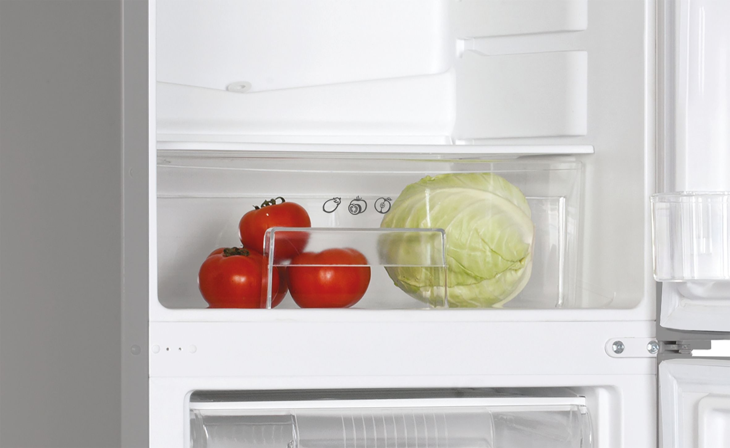Interior de refrigerador con tomates y repollo en un cajón para verduras, puerta abierta.