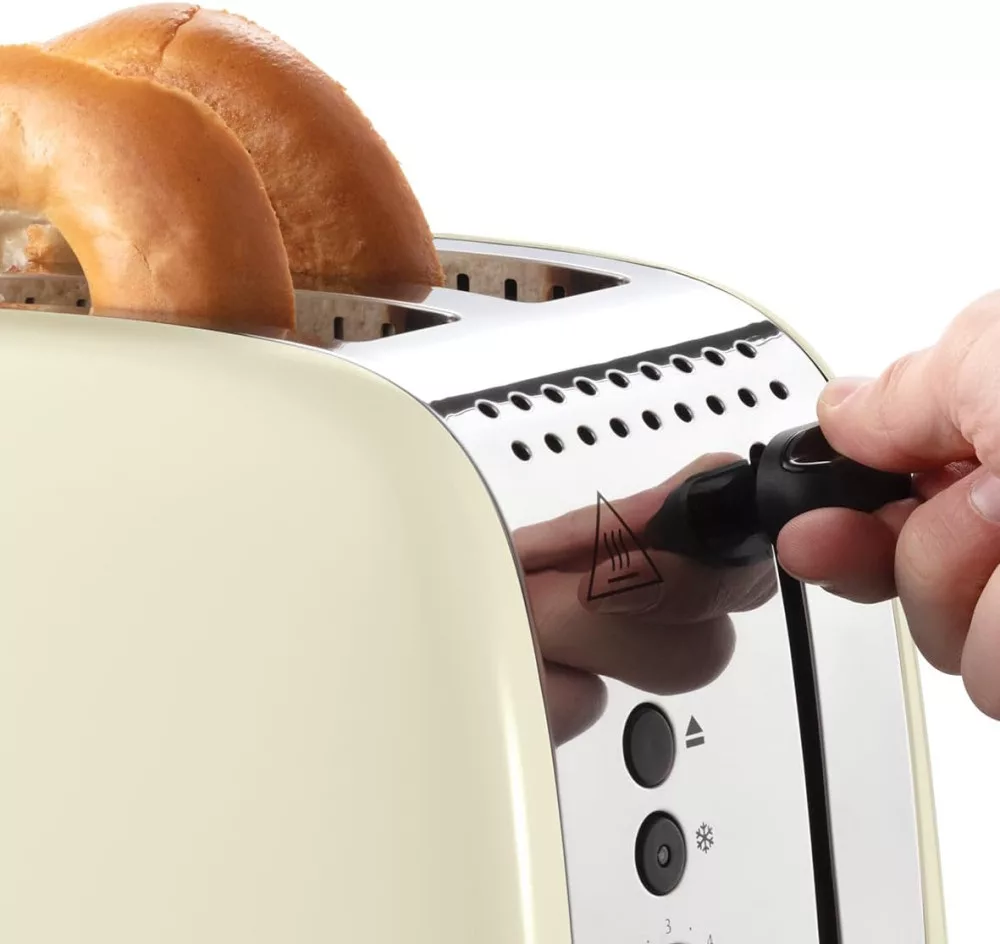 Mano che inserisce la spina in un tostapane retrò color crema con bagel all'interno, primo piano, sfondo bianco.