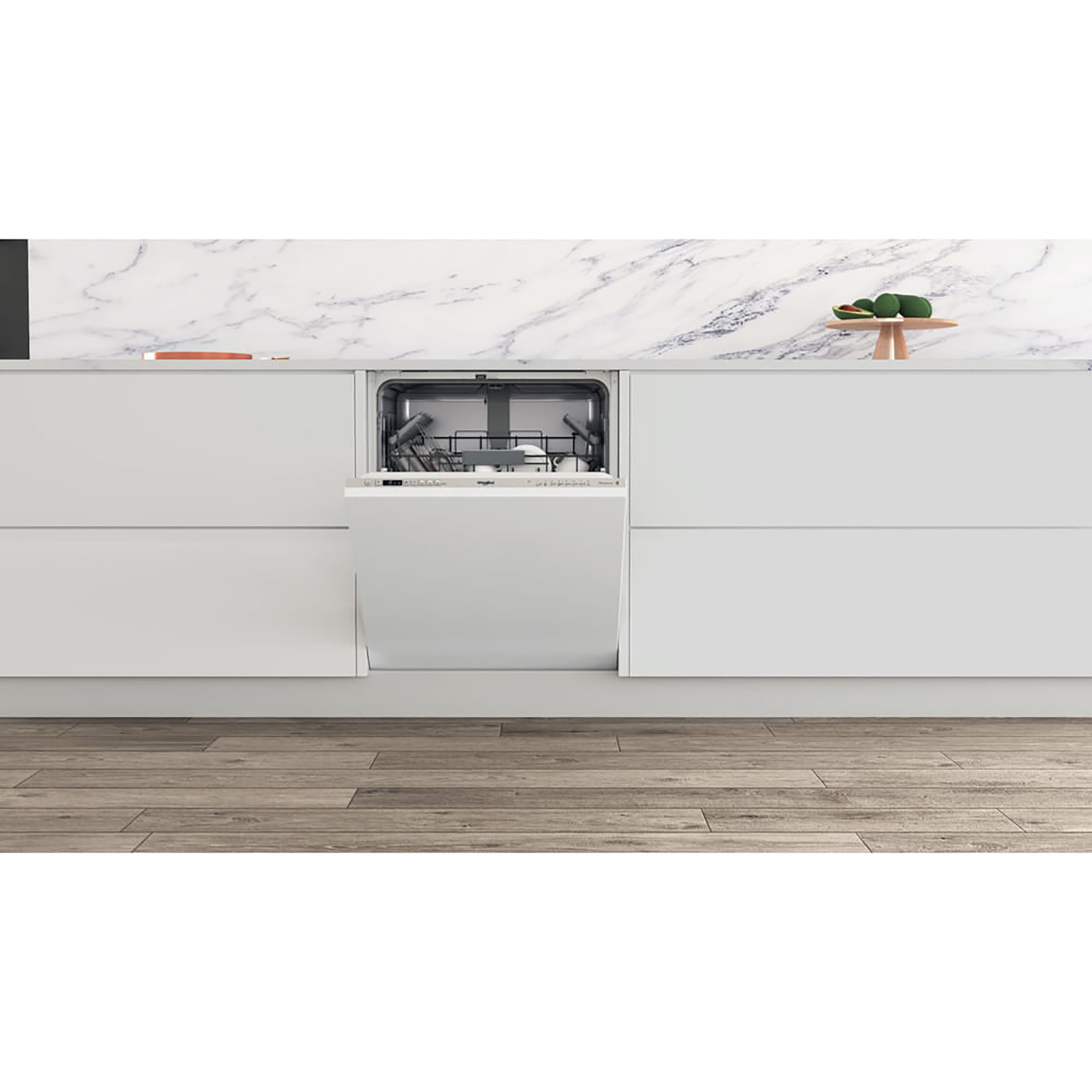 Una lavastoviglie bianca integrata in una cucina bianca con pavimento in legno, un tavolino in legno a destra.