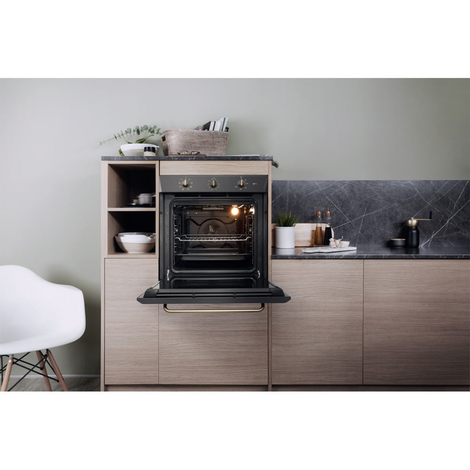 Cucina con forno aperto, inserito in mobili in legno. Un piano di lavoro è visibile sullo sfondo.