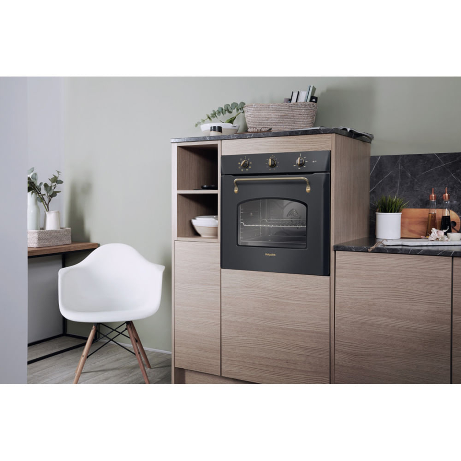 Cucina con forno e armadietto. Sedia bianca. Armadi in legno. Il forno è nero. Piano di lavoro in marmo.