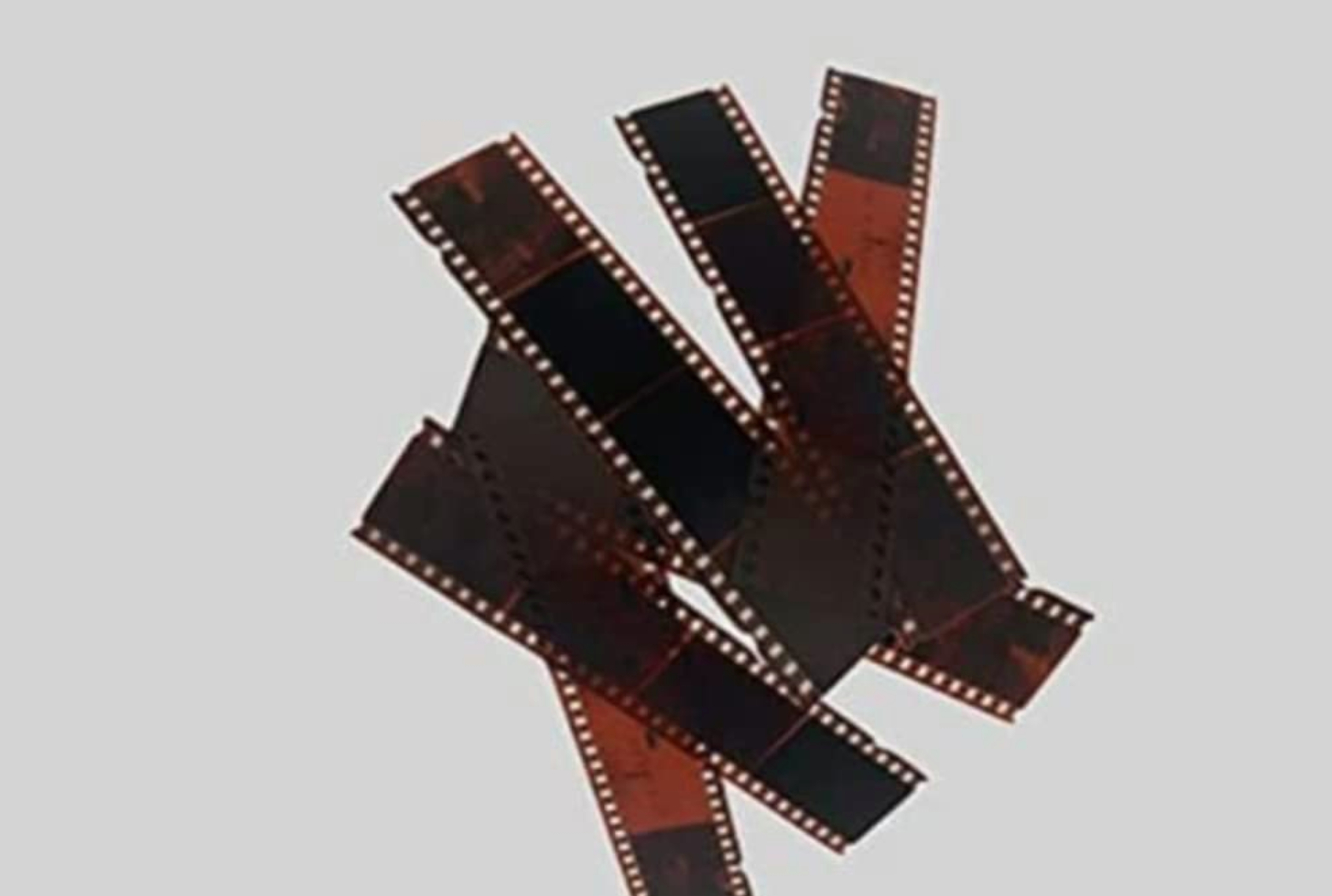 Filmstreifen-Negative auf hellgrauem Hintergrund verstreut.