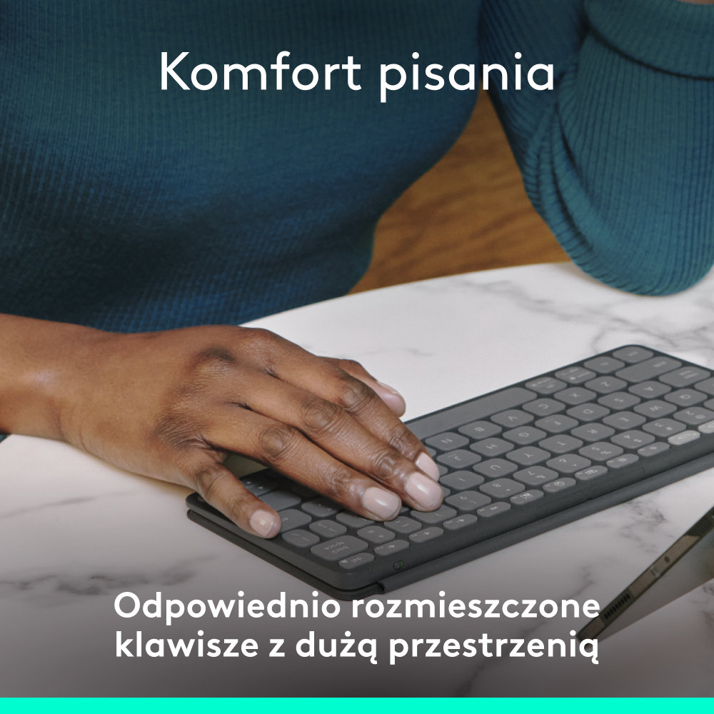 Dłoń osoby na klawiaturze. Tekst mówi: Komfort pisania. Odpowiednio rozmieszczone klawisze z dużą przestrzenią.