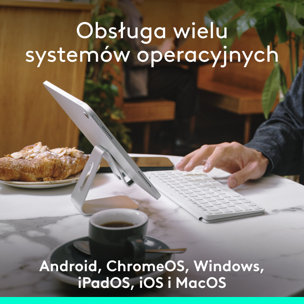 Tablet podparty klawiaturą, filiżanką i rogalikiem z tekstem po polsku.