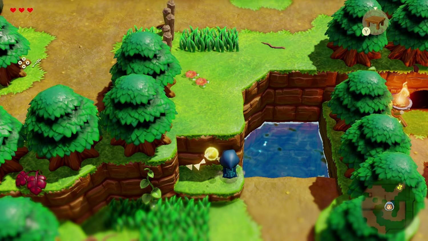 Una escena de juego 3D con Link en una plataforma cerca del agua, árboles y una entrada a una cueva.