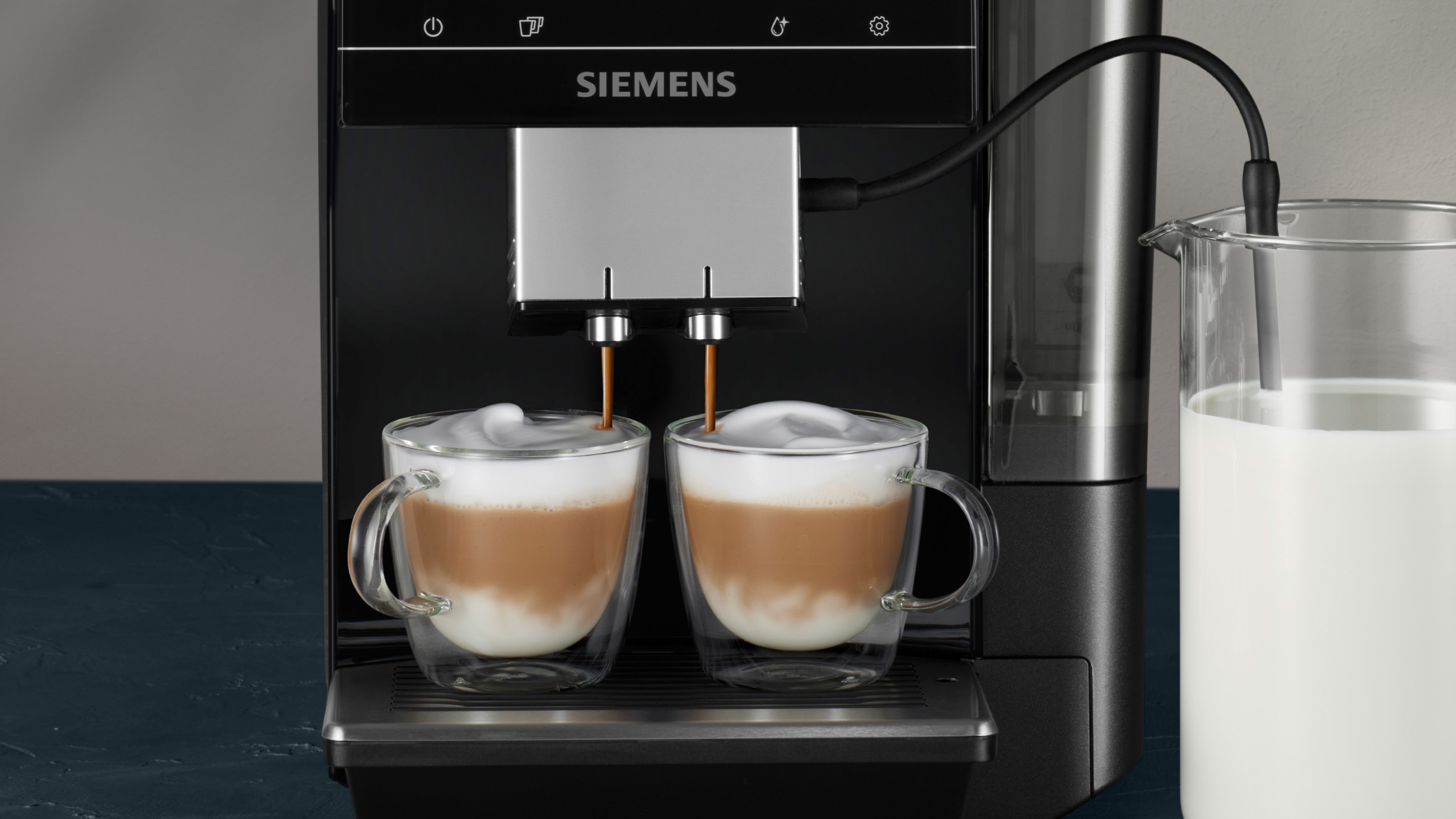 Eine Kaffeemaschine, die Kaffee in zwei Gläser mit Milchschaum ausgibt.