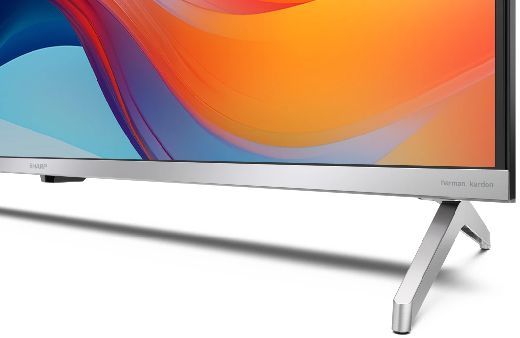Srebrny stojak pod telewizor z marką 'harman kardon', ekran TV powyżej.