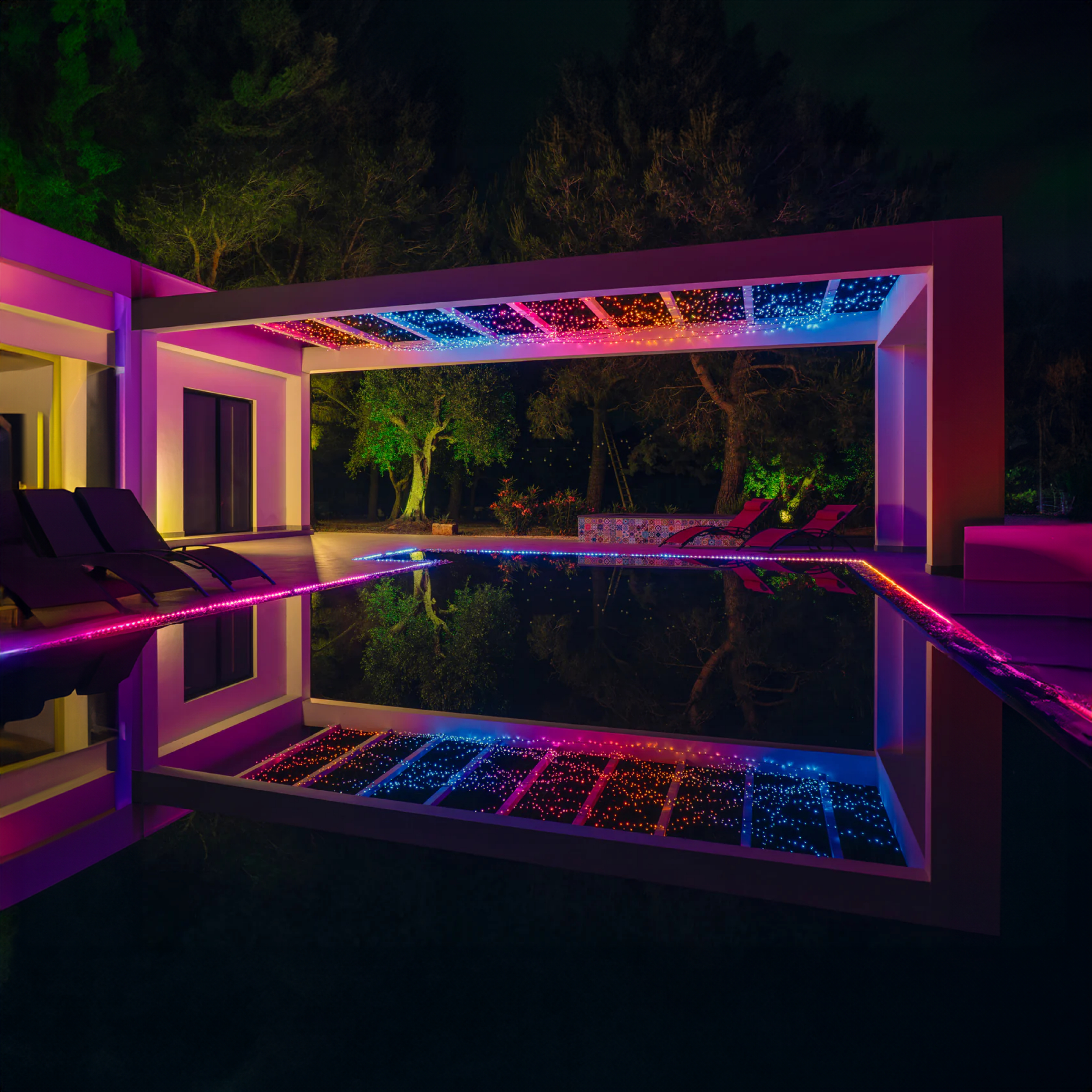 Nachtszenen eines Pools und einer Terrasse mit bunten Lichtern. Bäume sind im Hintergrund. Das Wasser reflektiert Lichter.