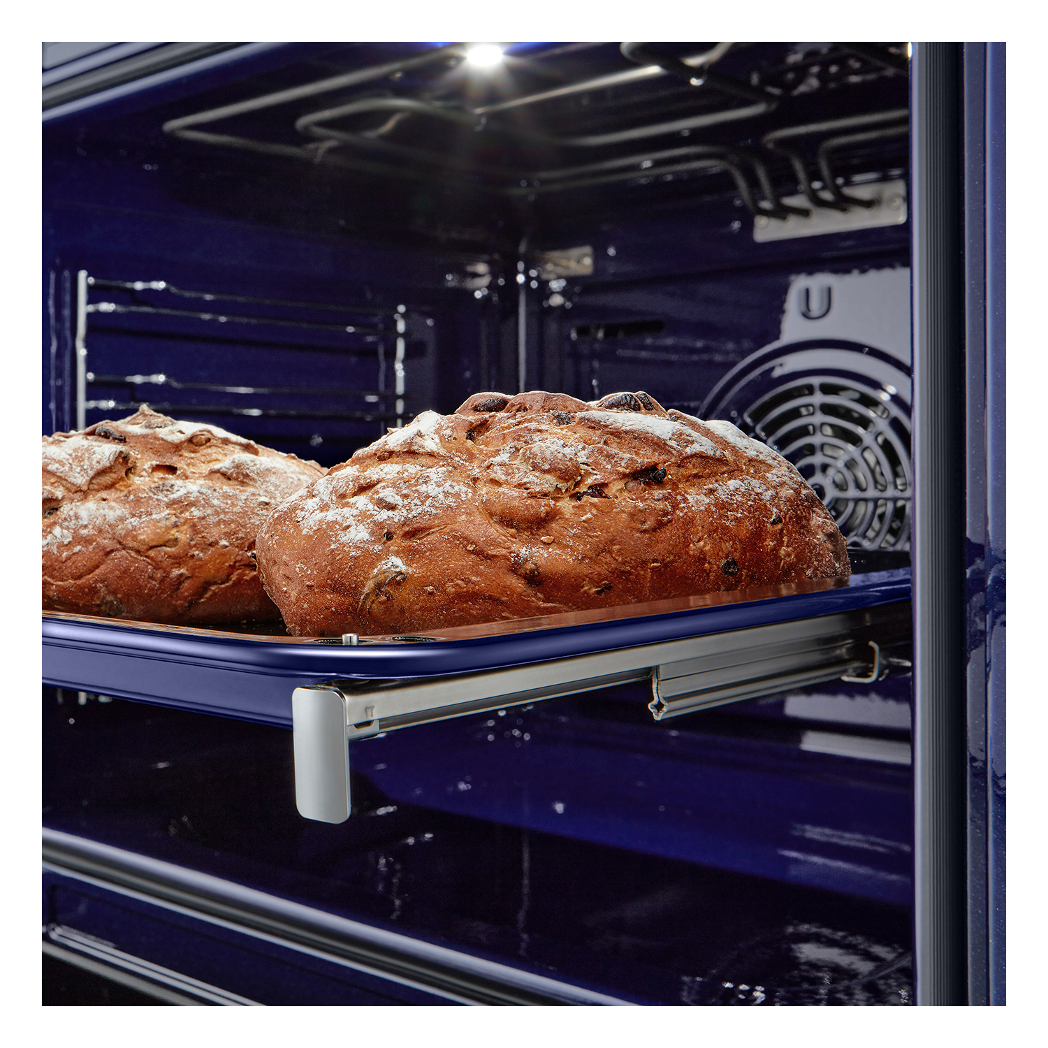 Due pagnotte di pane che cuociono in forno. L'interno è blu scuro, con una ventola e luce.