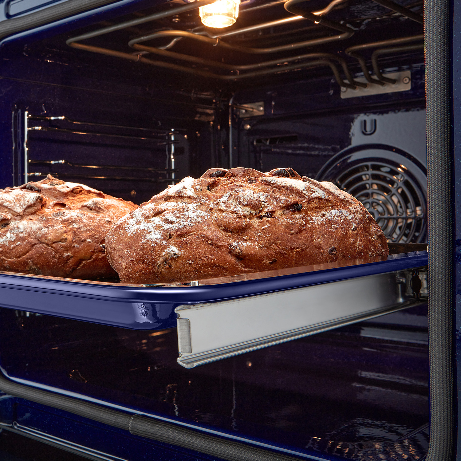 Due pagnotte di pane all'interno di un forno, illuminate da una luce calda.
