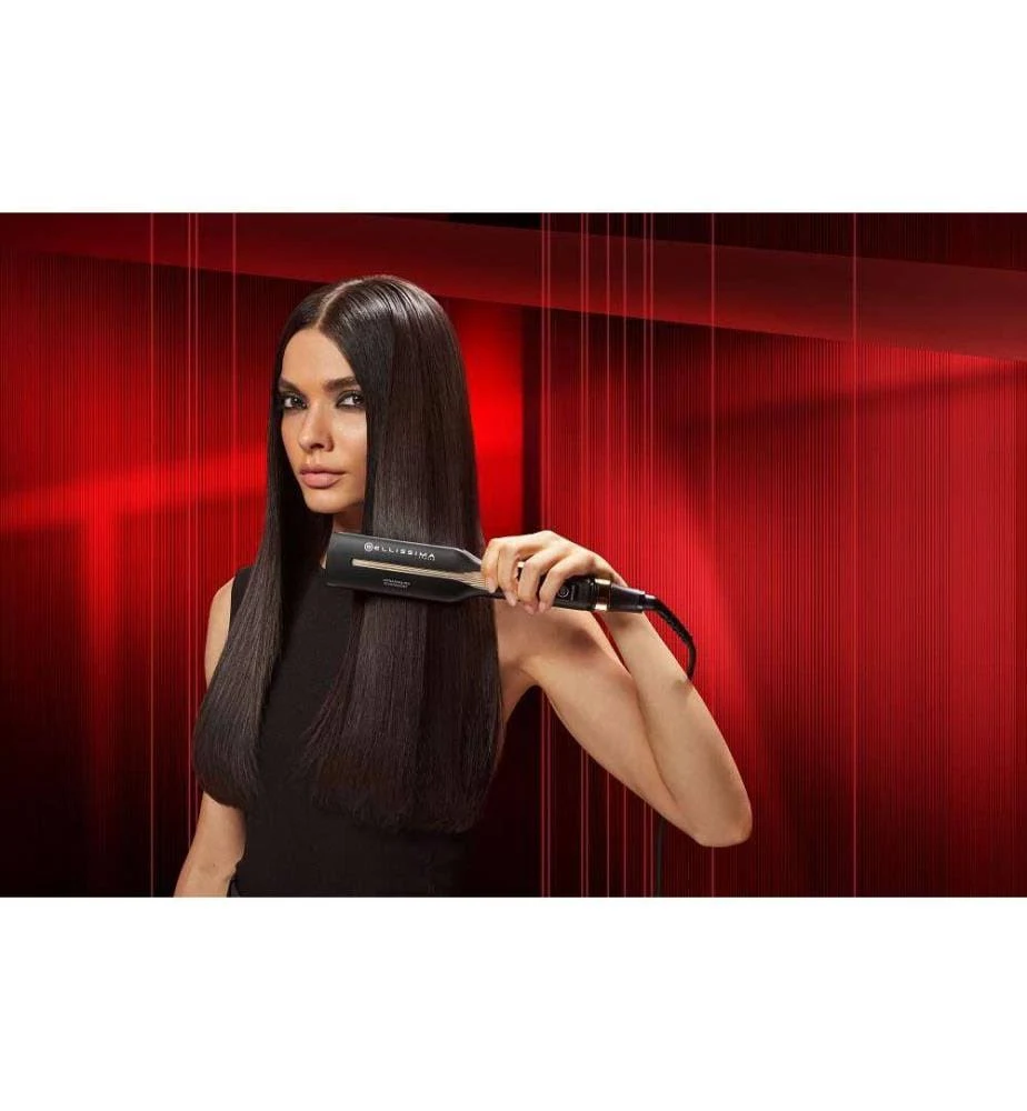 Mujer alisando su cabello con una plancha negra.