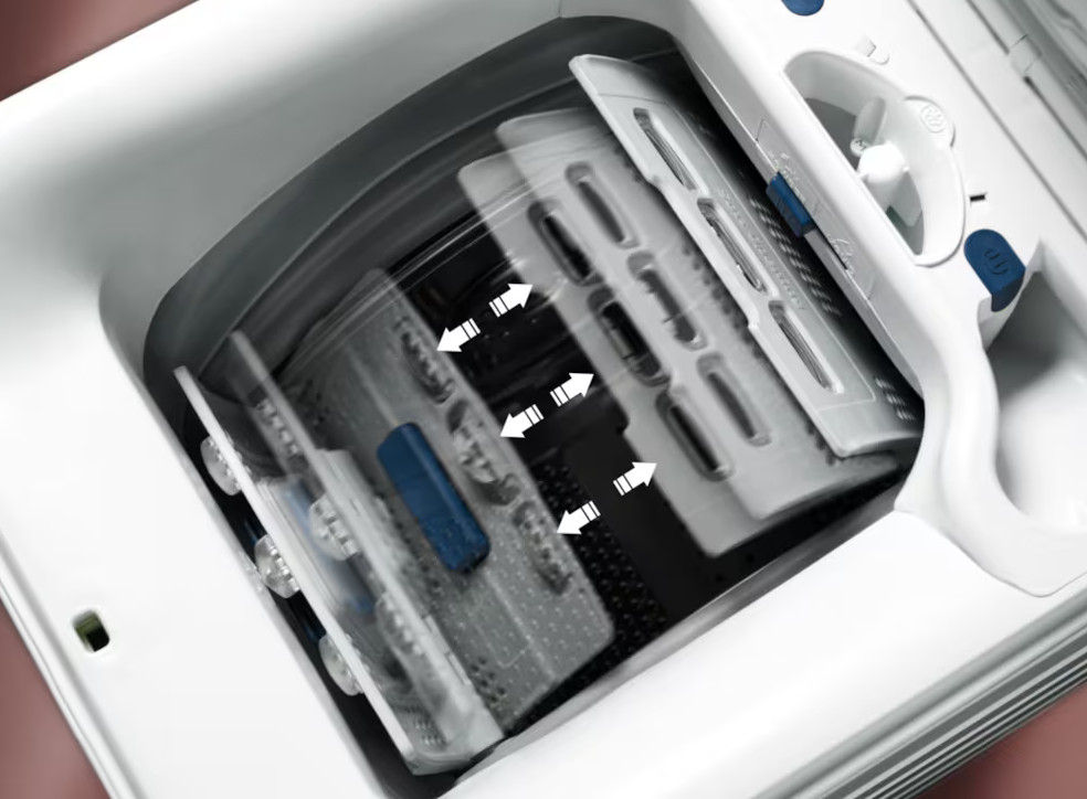 Wewnątrz pralki, bęben z płetwami, strzałkami i białymi częściami maszyny. Białe tło.