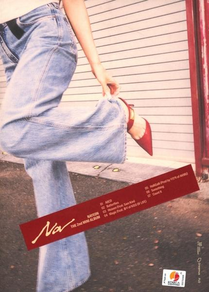 Eine Frau in Jeans und roten Absätzen justiert ihren Schuh in der Nähe eines roten Covers.