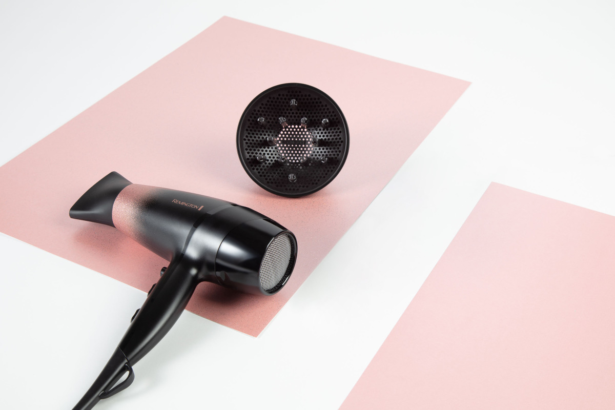 Asciugacapelli e diffusore neri su sfondo rosa e bianco. Marchio Remington visibile.
