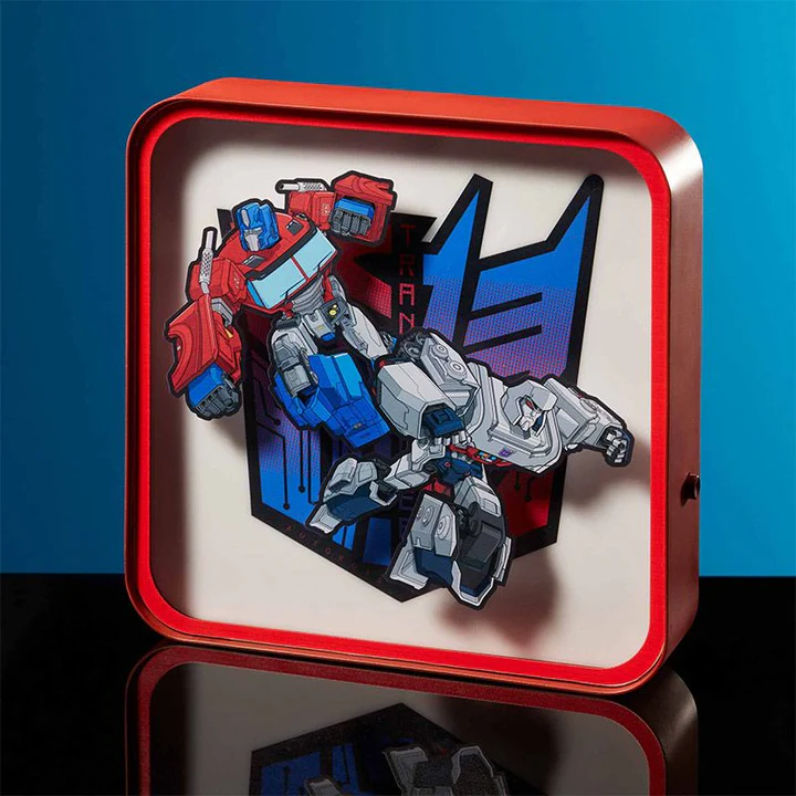 Roter Leuchtkasten mit Transformers-Charakteren Optimus Prime und Megatron vor blauem Hintergrund.