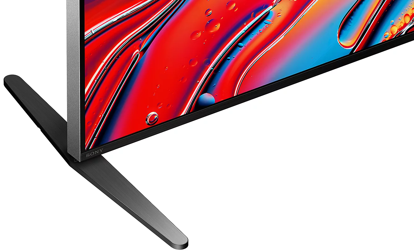 Zbliżenie podstawy telewizora i ekranu telewizora wyświetlającego kolorową sztukę abstrakcyjną.