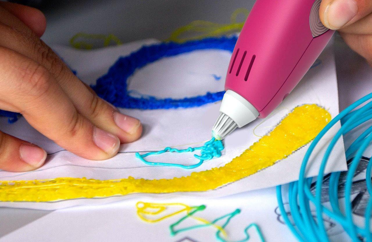 Eine Person, die einen 3D-Stift benutzt. Der Stift ist rosa und kreiert blaue und gelbe Designs.