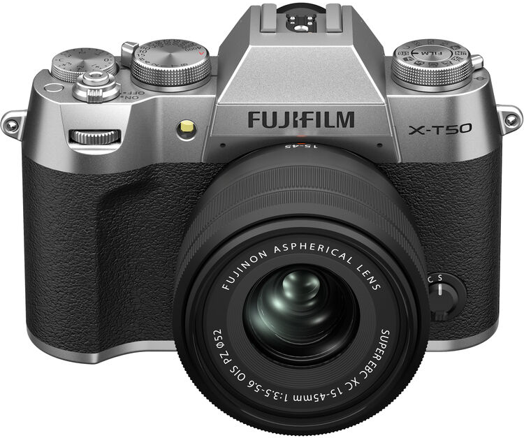 Ezüst Fujifilm kamera fekete objektívvel, fehér háttér előtt, enyhe árnyékkal.