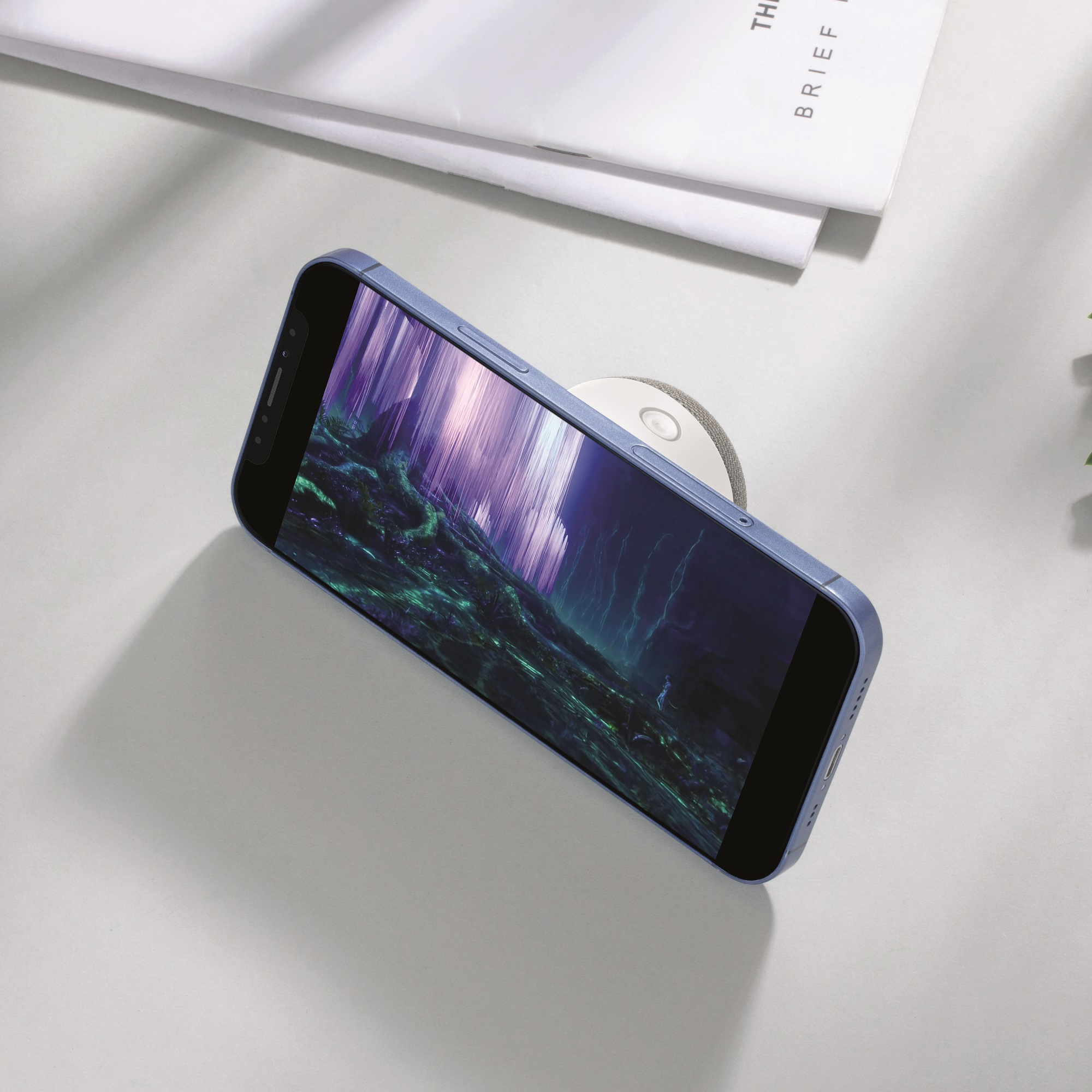 Blaues Telefon mit Landschaftsbildschirm auf heller Oberfläche.