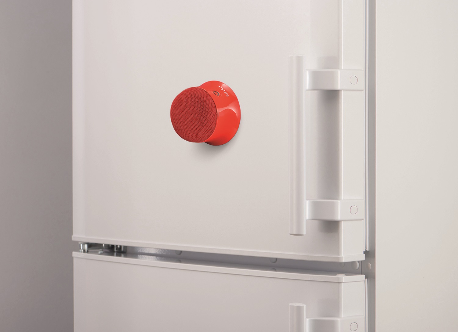 Roter magnetischer Lautsprecher an einer weißen Kühlschranktür befestigt.
