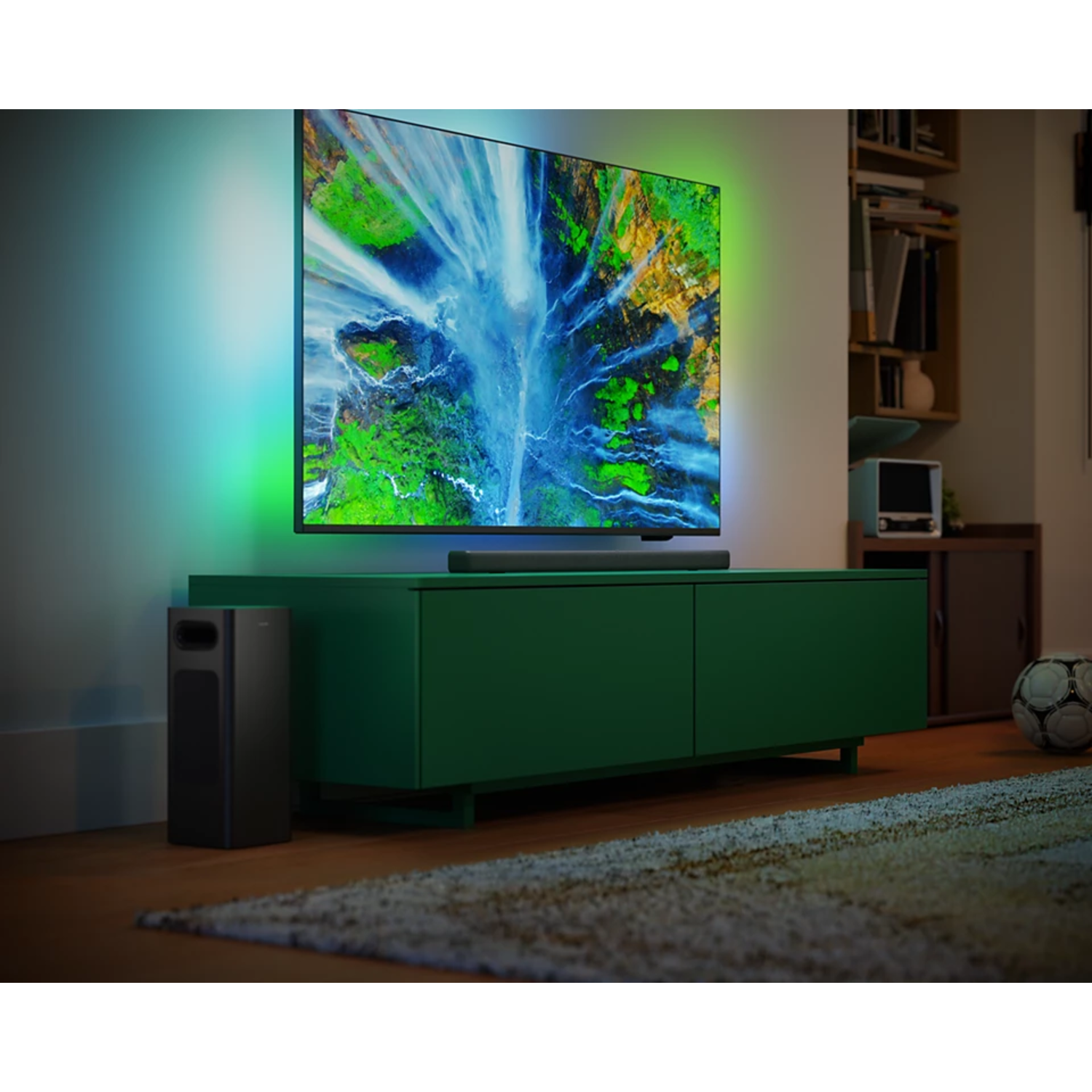 Un salon avec une grande télévision sur un meuble vert et un caisson de basses.