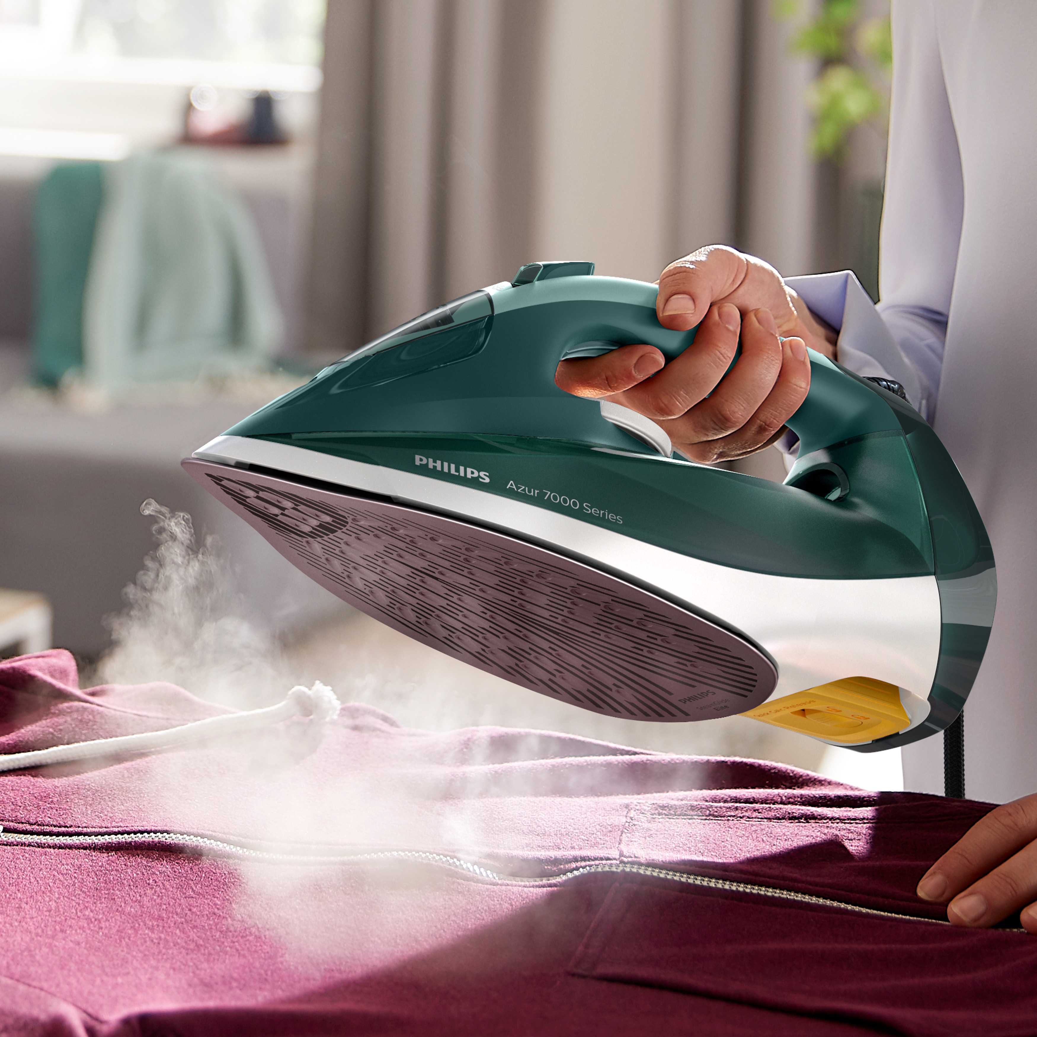 Una persona planchando una chaqueta morada con una plancha verde Philips Azur.