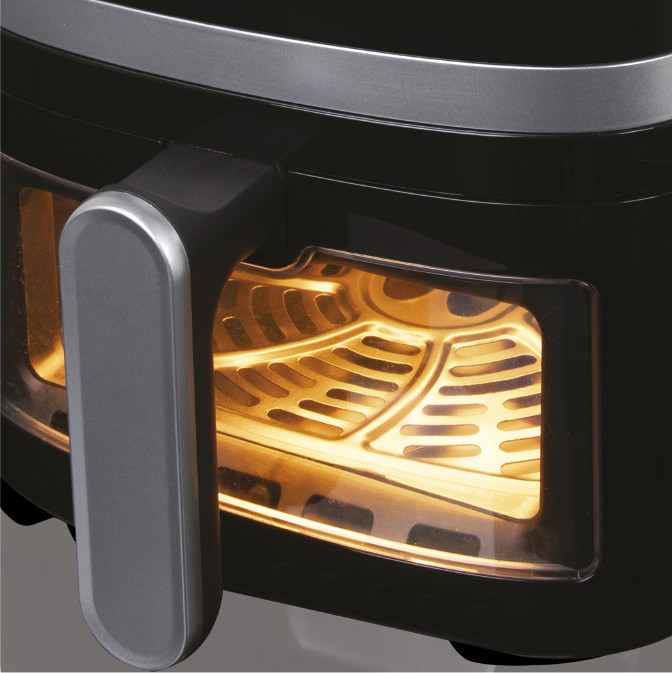 Friteuse à air noire avec intérieur éclairé. Poignée grise. Éléments chauffants visibles. Fond noir.