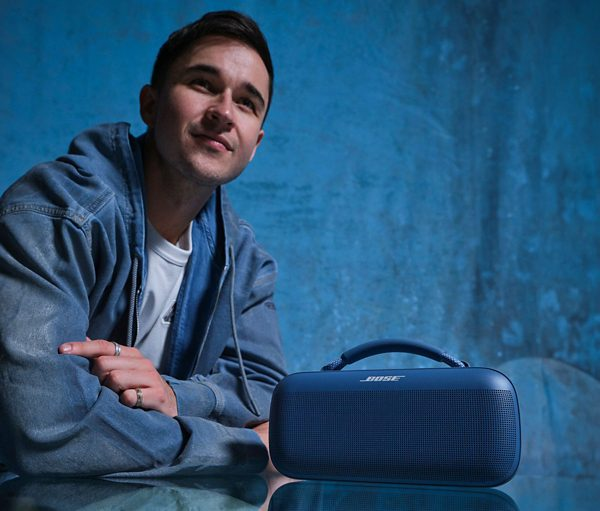 Uśmiechnięty mężczyzna z niebieskim głośnikiem na niebieskim tle.