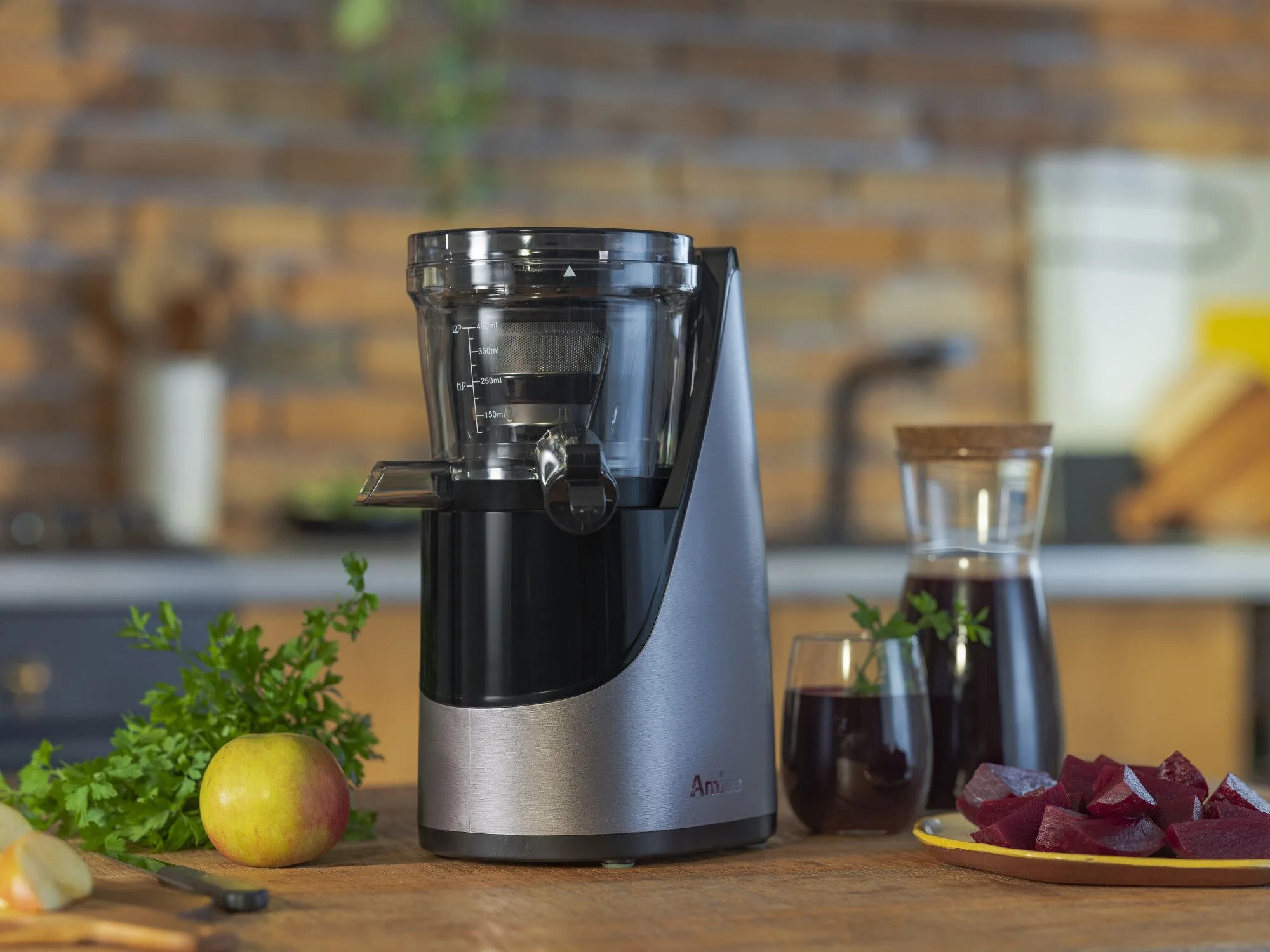 Wyciśnięta sokowirówka ze szklanką soku, burakami, jabłkiem i pietruszką na stole.