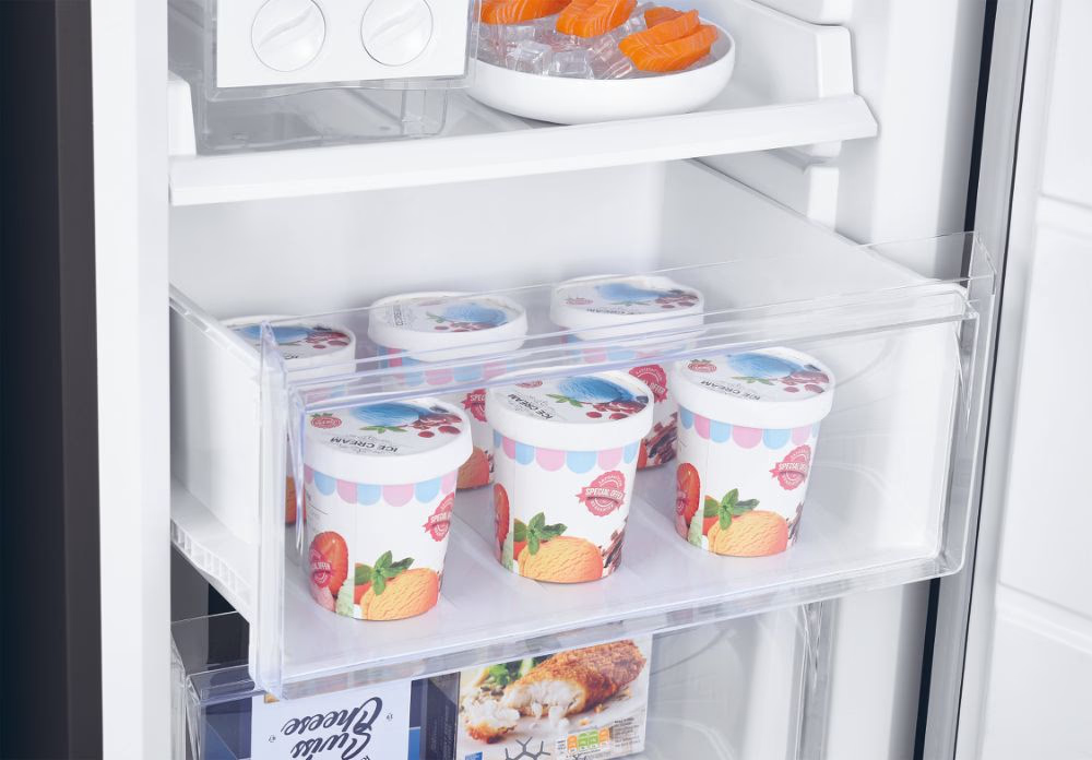 Cassetto del frigorifero pieno di vaschette di gelato, con altri articoli congelati visibili.
