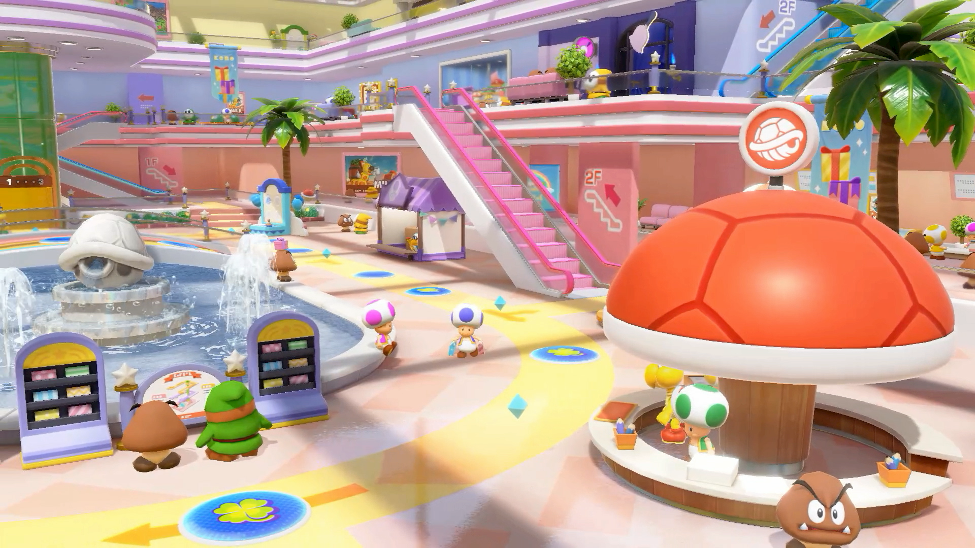 Una scena di videogioco colorata in un centro commerciale. I personaggi sono in un centro commerciale con una fontana e una scala mobile.
