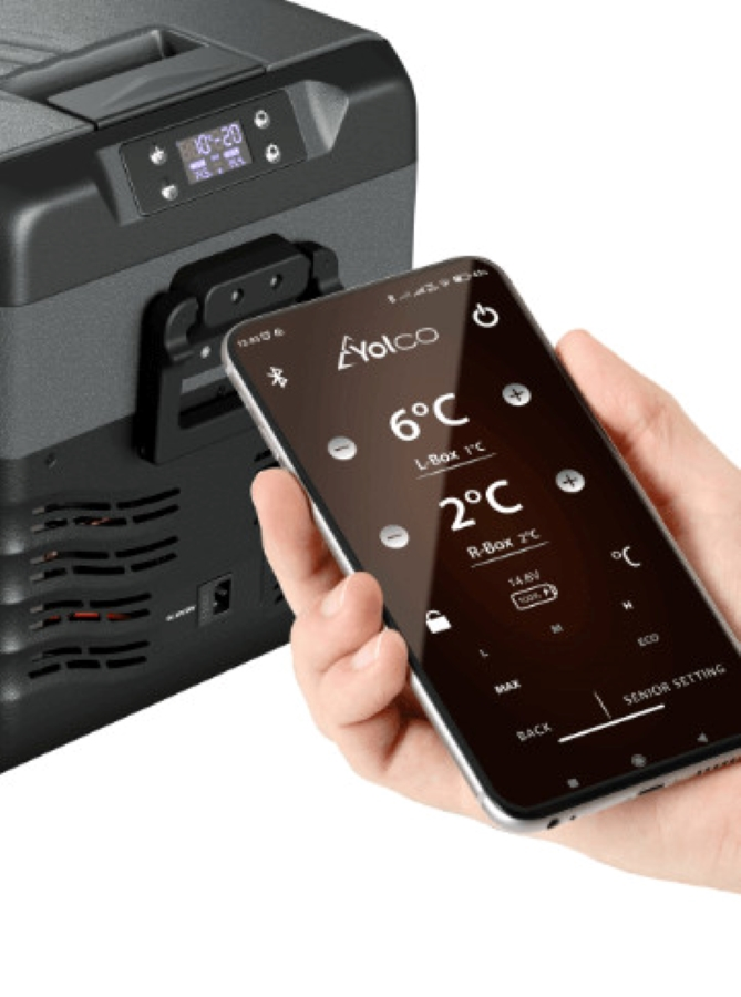 Dłoń trzymająca telefon, kontrolująca przenośną zamrażarkę.