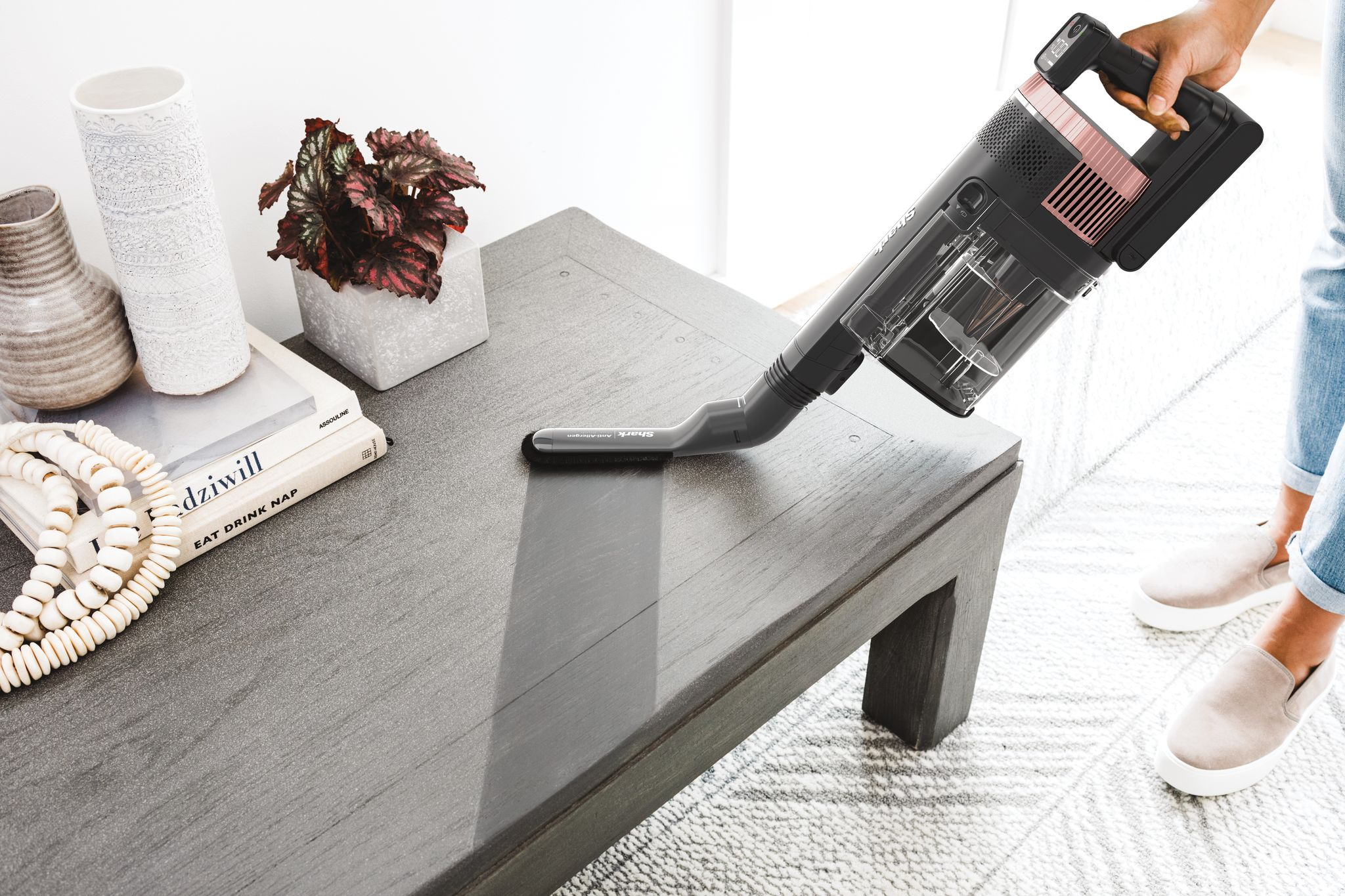 Une personne qui passe l'aspirateur sur une table en bois avec un aspirateur à main.