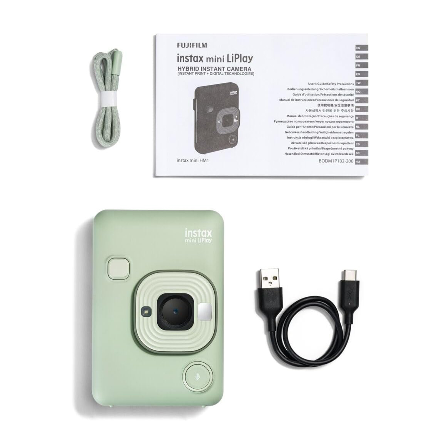 Una fotocamera istantanea verde, accessori e manuale su una superficie bianca.