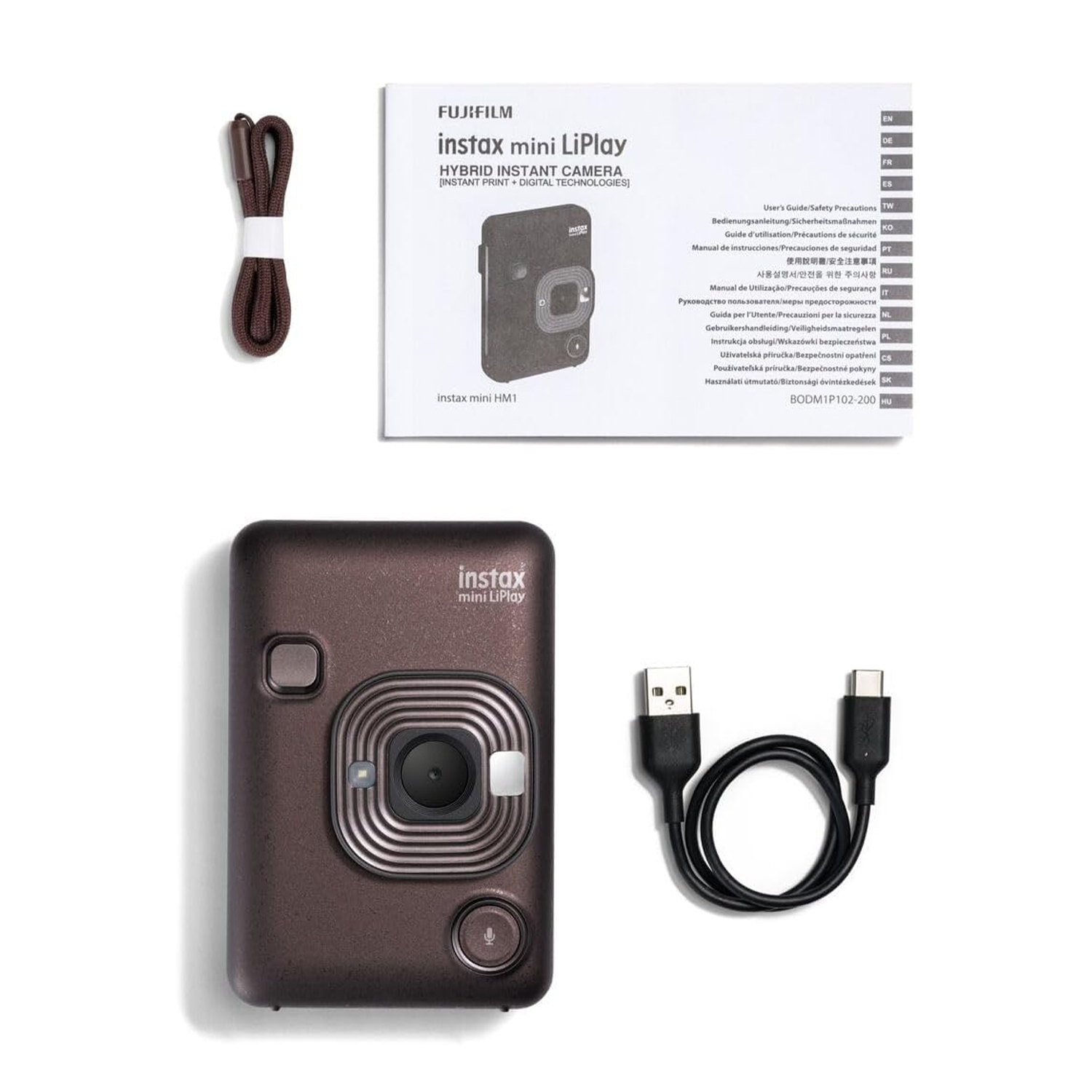Una fotocamera istantanea marrone, istruzioni, un cinturino e un cavo USB su una superficie bianca. La fotocamera è centrata.